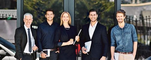 Fünf freundliche Geschäftsleute vor einem Bürogebäude